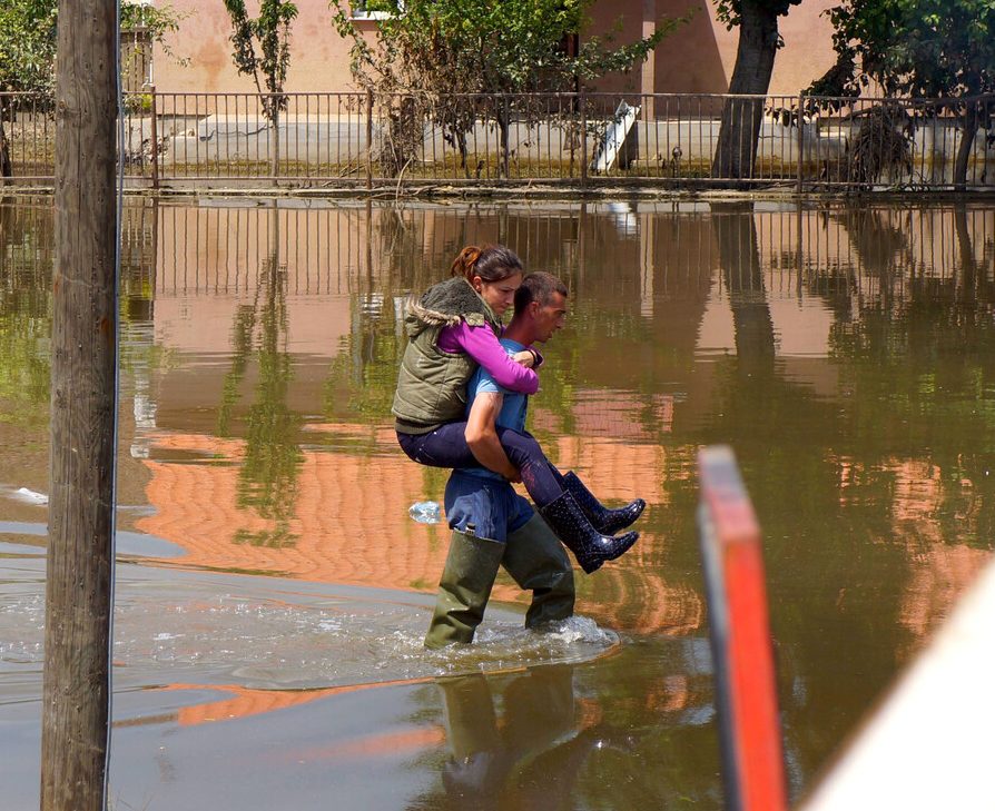 Ein Mann trägt eine Frau durch die Wasserfluten nach den Überschwemmungen in Serbien, 2014.