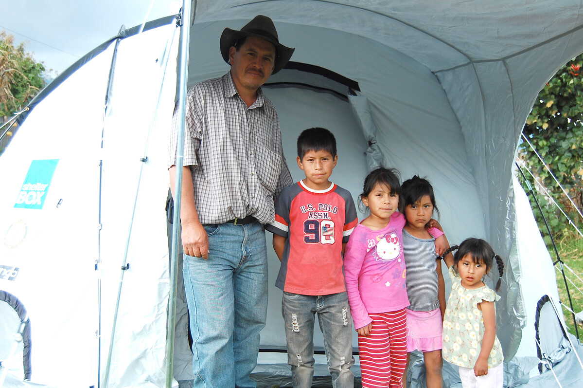 Ein Mann mit seinen Kindern vor einem ShelterBox Zelt nach dem Vulkanausbruch in Guatemala