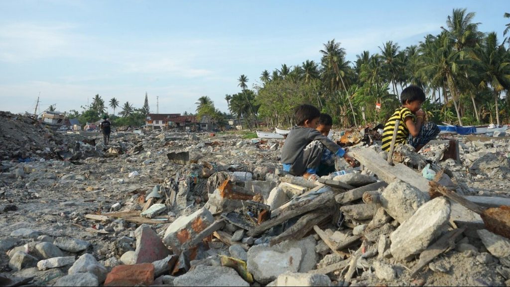 Kinder, die in Häuserruinen spielen, welche durch ein Erdbeben und einen Tsunami in Indonesien entstanden sind