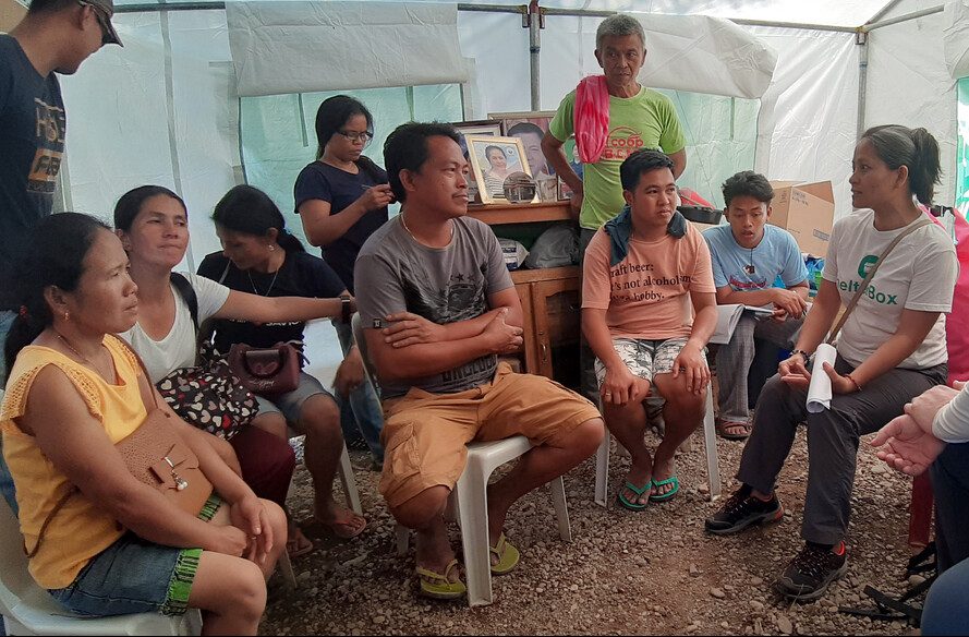 Menschen versammeln sich in einem Zelt in den Philippinen, um den Einsatz nach drei Erdbeben zu besprechen.