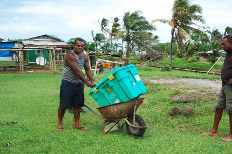 Übernimm ein Ehrenamt bei ShelterBox. Ein Mann transportiert eine ShelterBox in einer Schubkarre