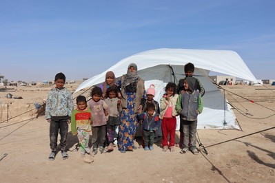Eine Frau steht mit ihren Kindern vor einem Zelt in Syrien