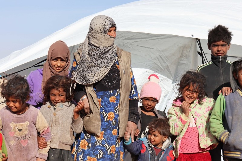 Eine Frau steht mit ihren Kindern vor einem Zelt in Syrien